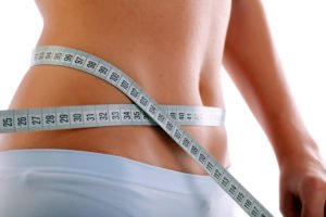 Close up of a slim beautiful waist with measuring tape.